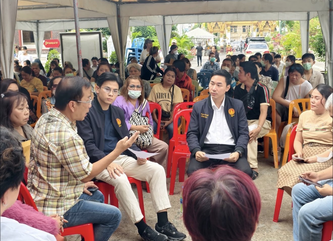 Thanapat and the constituency team listen to vendors during a discussion near Wat Chakkrawat