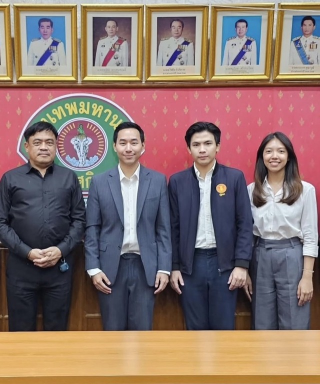 Thanapat stands with the working group and officials in front of the Bangkok Metropolitan Administration emblem